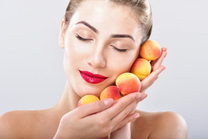 Beautiful woman holding a juicy apricots, peaches
